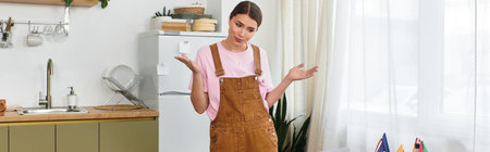 In a stylish kitchen, a young woman gestures, looking puzzled about something unclear.のeditorial素材