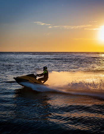 A rider skillfully navigates a jet ski against a stunning sunset backdrop on the open water.の素材