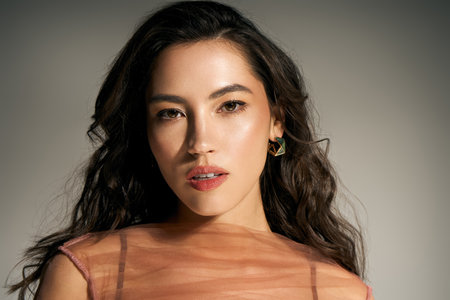 A young woman radiates charm in stylish summer attire, full of confidence in a lively setting.のeditorial素材