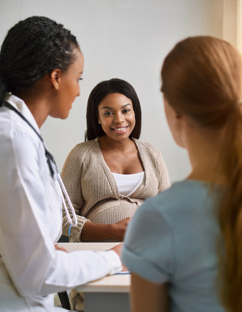 An expectant mother smiles while consulting with gynecologist about her prenatal care.の素材