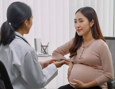 A gynecologist calmly reviews health assessments with a pregnant woman in the hospital.の素材
