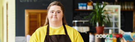 A confident young woman with Down syndrome stands proudly in a vibrant cafe outfit.のeditorial素材