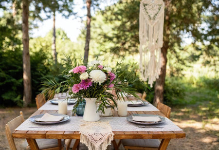 An outdoor table is beautifully set surrounded by lush greenery and flowers.の素材