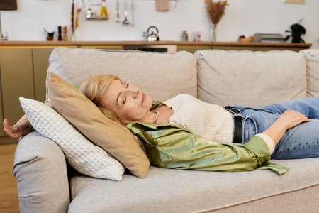 A serene senior woman relaxes on a couch, embracing the calmness of her cozy living space.の写真素材
