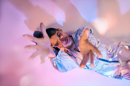 A young woman showcases holographic fashion in an experimental pose among vibrant colors.