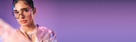 A young woman models chic, holographic attire against a vibrant backdrop.