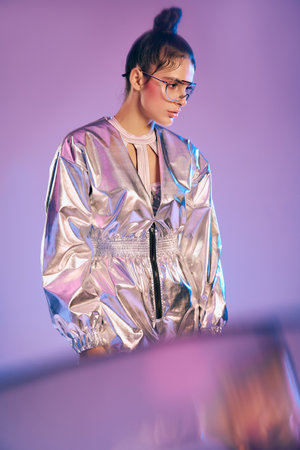 A young woman displays her trendy holographic outfit in an artistic setting.
