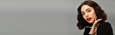 A beautiful young woman with striking red lips poses elegantly against a grey background, bannerのeditorial素材