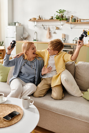 Laughter fills the air as a mother and her son bond over a fun gaming experience on the couch.の写真素材