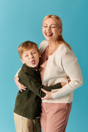 A mother and son embrace joyfully, their playful smiles bright against a vibrant backdrop.の写真素材
