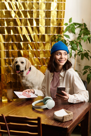 A young woman smiles while seated at a table with her labrador, enjoying a relaxed cafe atmosphere.のeditorial素材