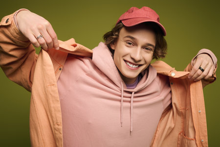 A cheerful young man flaunts his stylish outfit with confident charisma amidst a lively setting.のeditorial素材