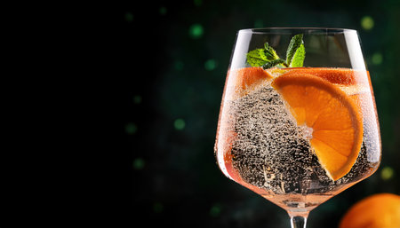 Refreshing summer drink with sparkling bubbles, orange slices, and mint leaves inviting enjoyment.の素材
