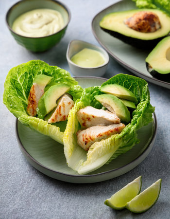 Vibrant and fresh summer dish featuring juicy grilled chicken and creamy avocado in lettuce wraps.の素材