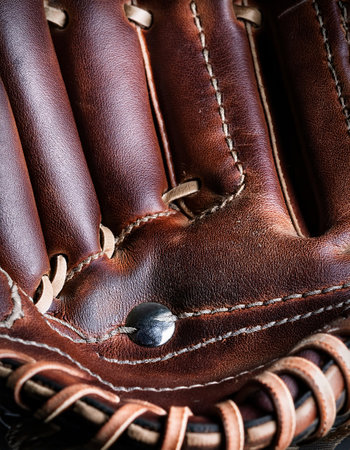 Close up view of a weathered baseball glove showcasing its durability and intricate stitching.の素材