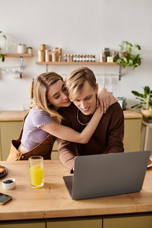 A loving couple enjoys each others company while engaging with a laptop in their modern kitchen.の写真素材