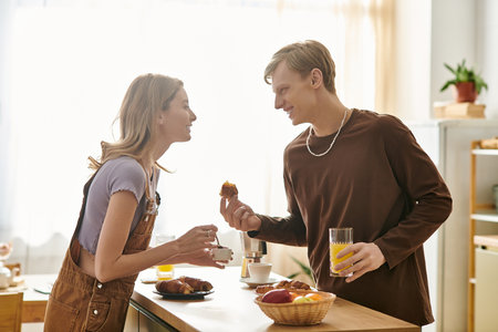 A young couple enjoys a romantic breakfast, laughing and sharing food in their stylish home.