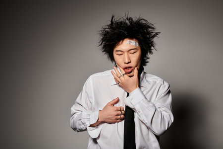 An Asian man in stylish clothes toughing face after fightの写真素材