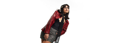 Confident young asian woman showcases her fashionable attire and style against a sleek background.