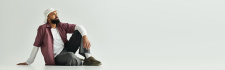 A stylish young man relaxes on the floor, deep in thought and showcasing his fashion.の写真素材