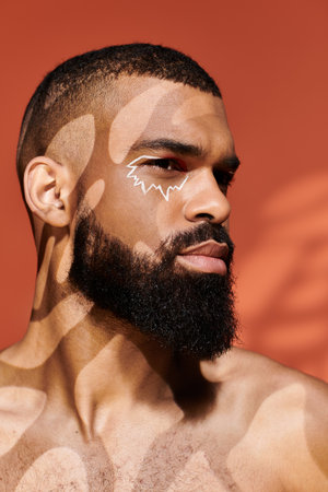 Young fashion forward man showcases a striking face design while exuding charm and confidence.の写真素材