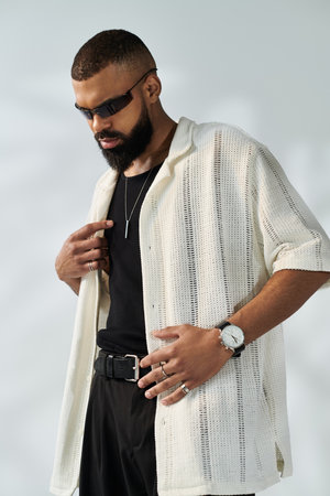 A stylish young man poses confidently in modern attire and accessories.のeditorial素材
