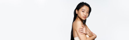 A young asian woman exudes confidence while posing gracefully, highlighting her natural beauty.の写真素材