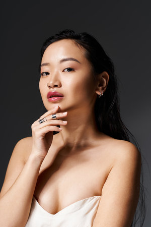 A young asian woman poses thoughtfully, showcasing her beauty and elegance under soft lighting.のeditorial素材