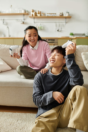A young asian couple shares laughter and joy while playing games at home, creating memories.
