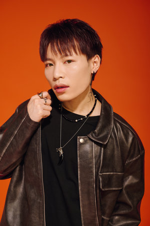 A handsome young asian man stands strikingly with a leather jacket, exuding confidence and styleのeditorial素材