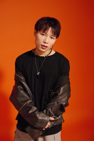 A handsome man stands with a relaxed posture, dressed in trendy attire, emanating charisma.