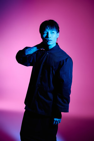 A stylish young Asian man poses effortlessly in captivating lighting.