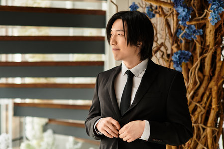 Handsome groom stands confidently, adjusting his attire for the big wedding moment.のeditorial素材