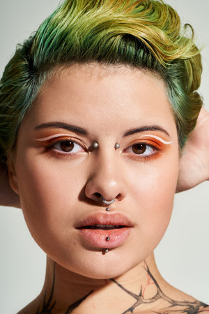 Stylish woman poses confidently with creative makeup and vibrant hair color in a chic setting