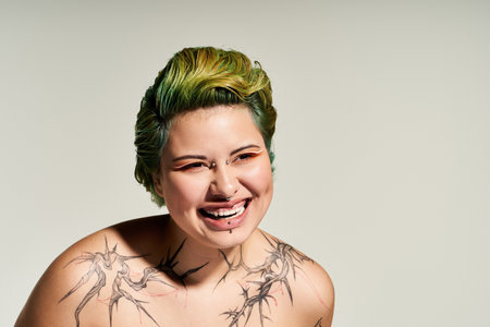 Vibrant hair complements a joyful young woman with striking tattoos and chic makeup.のeditorial素材