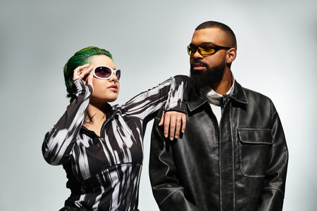 A stylish young couple showcases their unique outfits and sunglasses in a modern studio setting.のeditorial素材