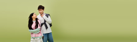 A stylish couple playfully shows their love against a lively green backdrop.のeditorial素材