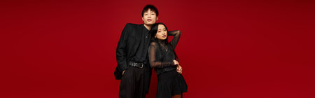 A stylish couple radiates romance against a bold red backdrop, showcasing their fashion.のeditorial素材