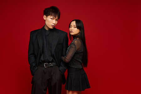A stylish couple poses closely, displaying their chemistry against a vibrant red backdrop.のeditorial素材