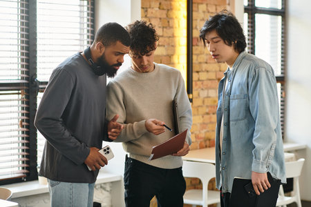 Colleagues collaborate in a contemporary workspace, reviewing project notes and sharing ideas.の写真素材