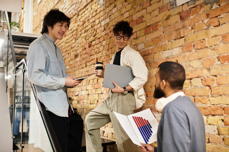 Three team members collaborate in a vibrant office, sharing ideas over coffee and tech.