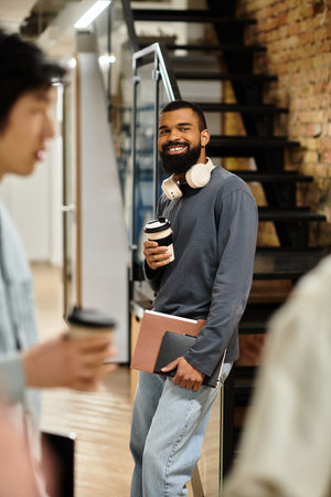Colleagues chat casually as a man smiles and sips coffee in a lively office.