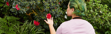 In a greenhouse, a young woman nurtures plants and admires blooming flowers.のeditorial素材