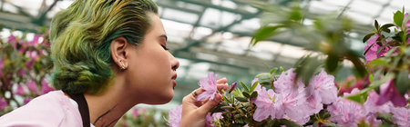 Engaged in nurturing beautiful blossoms, a young woman enjoys the tranquility of a greenhouse.のeditorial素材