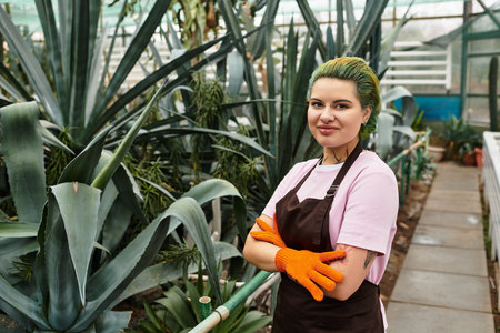 A young woman in a greenhouse nurtures plants, showcasing her vibrant personality.のeditorial素材