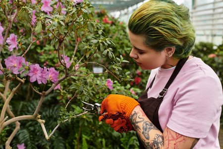 A lively young woman prunes beautiful flowers in a greenhouse, embracing her passion.