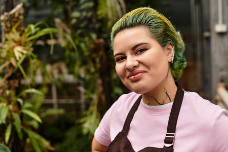 A young woman passionately engages in nurturing plants inside a lively greenhouse full of greenery.のeditorial素材