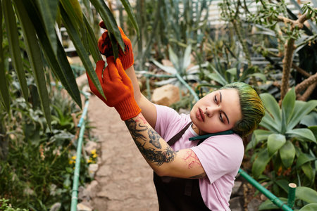 A young woman attends to plants in a lively greenhouse, showcasing her dedication and passion.