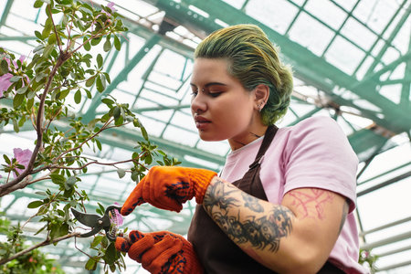 Carefully pruning flowers, the young woman enjoys her time nurturing the plants in the greenhouse.