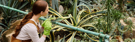 Focused on nurturing beautiful plants, a serene woman engages with nature in a greenhouse setting.